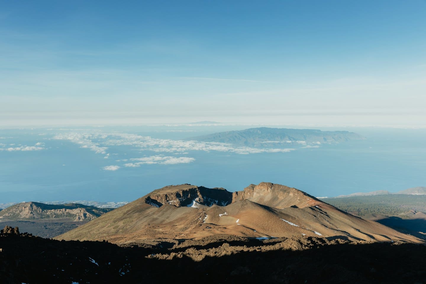 Volcanic mountain landscape meets the ocean under a clear blue sky.